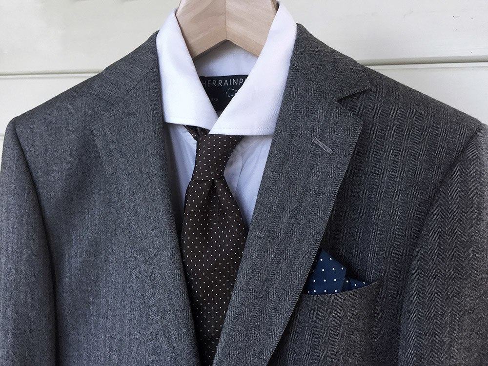 Understated medium gray wool suit with a white shirt, restrained tie and pocket square - an excellent choice for cocktail wear.